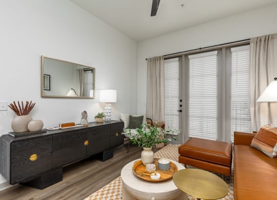 Model apartment living room with a leather couch and a dresser at Era apartments in Denton, TX