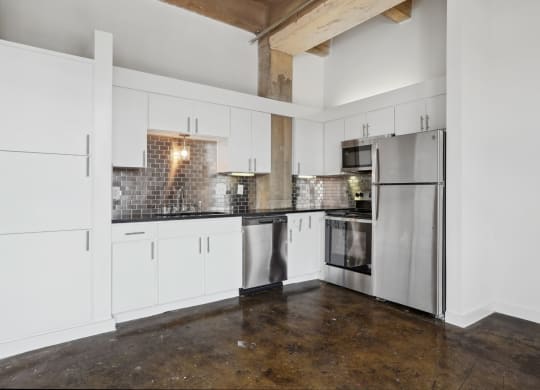 Farm and Ranch loft kitchen with white cabinets and stainless steel appliances | Deep Ellum Lofts in Dallas, TX