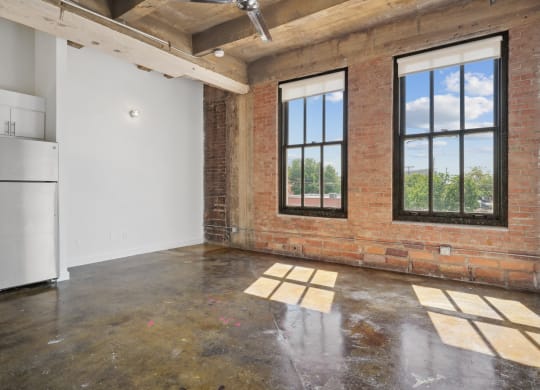 Farm and Ranch loft interior living area with polished concrete floors and brick accent wall | Deep Ellum Lofts in Dallas, TX