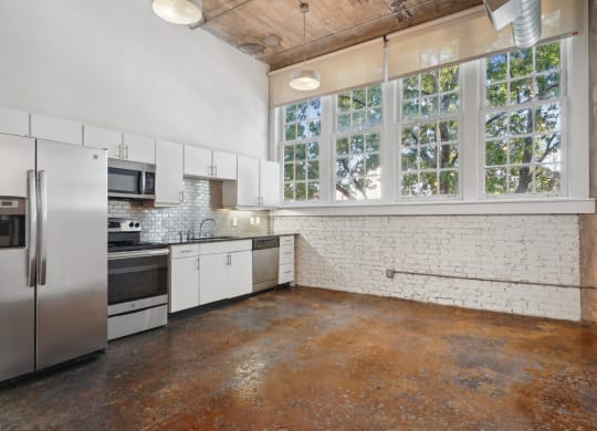 a kitchen with white cabinets and stainless steel appliances and a large window