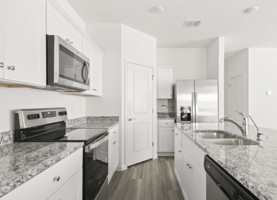 a kitchen with white cabinets and black appliances at Beacon at Meridian, Texas, 78245