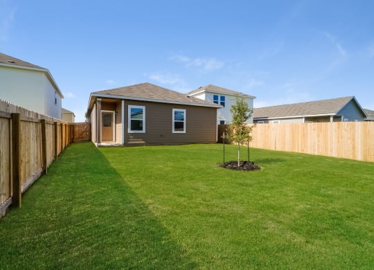 a backyard with green grass and a wooden fence at Beacon at Meridian, Texas