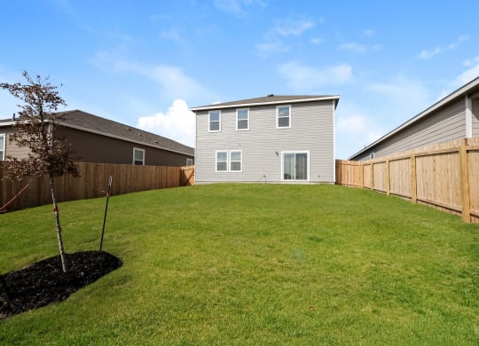 a backyard with a large lawn and a house in the background at Beacon at Meridian, San Antonio, TX 78245