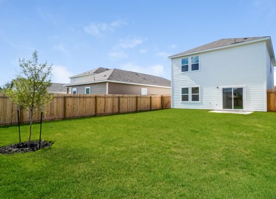 a backyard with green grass and a white house with a gray roof at Beacon at Meridian, San Antonio