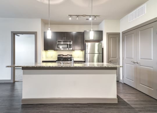 an empty kitchen with a large island with a granite counter top