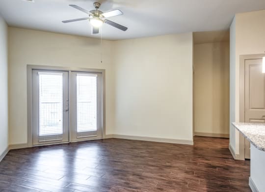 an empty living room with white walls and a ceiling fan