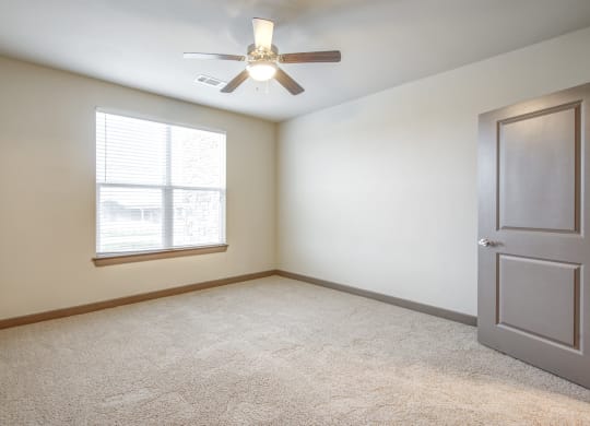 an empty room with a ceiling fan and a window