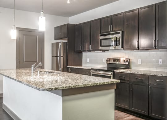 a kitchen with a marble counter top and black cabinets
