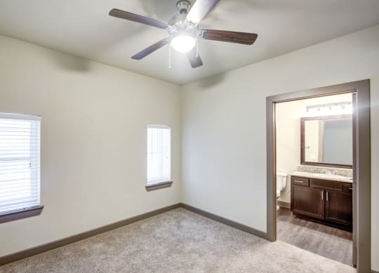 an empty bedroom with a ceiling fan and a mirror