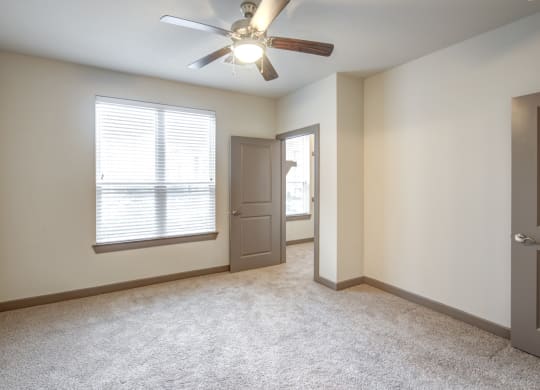 an empty living room with a ceiling fan and a window