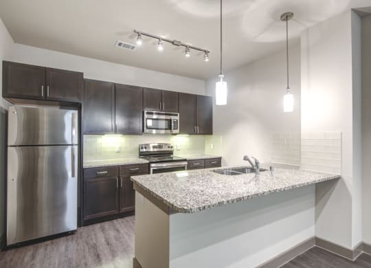 a kitchen with a granite counter top and stainless steel refrigerator