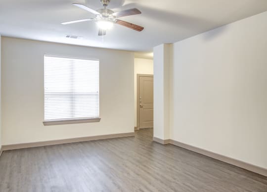 an empty living room with a ceiling fan and a window