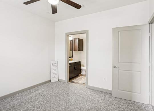 A bedroom with white walls, a closet, and a fan on the ceiling at GreenVue Apartments in Richardson, TX