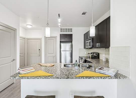 A kitchen with a granite countertop and dark cabinets at GreenVue Apartments in Richardson, TX