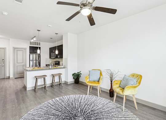 An open living room with a ceiling fan and grey rug at GreenVue Apartments in Richardson, TX