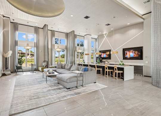 Clubhouse with a grey sofa set and a kitchen area at GreenVue apartments in Richardson, TX