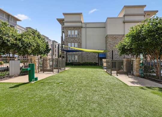 Dog park with a large grassy area and water fountain at GreenVue apartments in Richardson, TX
