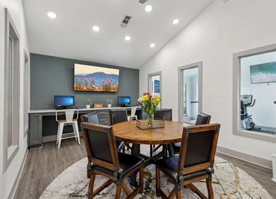 A business center with a wooden table and chairs and computers at Gwinnett Square Apartments in Duluth, GA