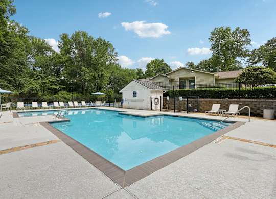 A large swimming pool surrounded by a fence and trees at Gwinnett Square Apartments in Duluth, GA