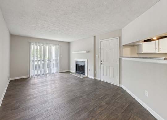 A living room with a fireplace and wooden floors at Gwinnett Square Apartments in Duluth, GA