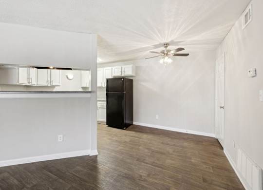 A dining room with a ceiling fan leading into the kitchen at Gwinnett Square Apartments in Duluth, GA