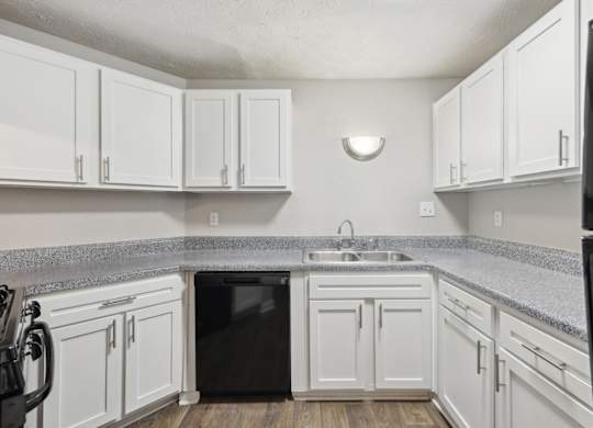A kitchen with white cabinets and black appliances at Gwinnett Square Apartments in Duluth, GA