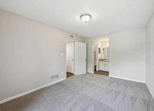 A bedroom with carpet leading to a bathroom and closet  at Gwinnett Square Apartments in Duluth, GA