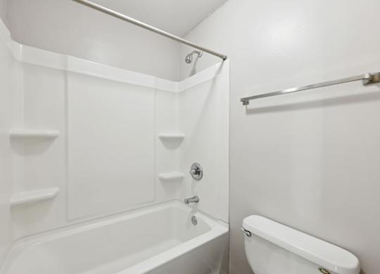 A white bathroom with a tub and toilet at Gwinnett Square Apartments in Duluth, GA
