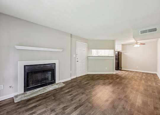 A living room with a fireplace that leads into the dining and kitchen area at Gwinnett Square Apartments in Duluth, GA
