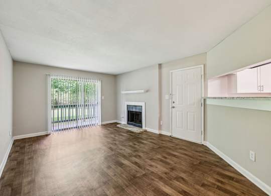 A living room with a fireplace and a glass door leading to a balcony at Gwinnett Square Apartments in Duluth, GA