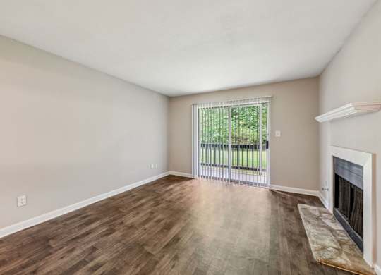 A living room with a fireplace and a sliding glass door leading to a balcony at Gwinnett Square Apartments in Duluth, GA