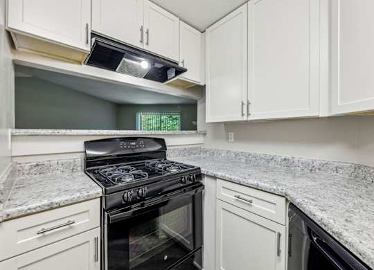 A kitchen with a black stove top oven and white cabinets at Gwinnett Square Apartments in Duluth, GA