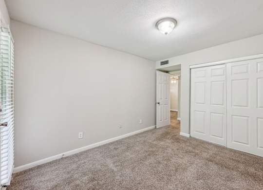 A bedroom with a closet and carpet at Gwinnett Square Apartments in Duluth, GA
