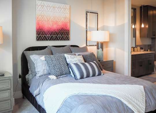 3 bedroom model third bedroom viewing a bed with pillows and a painting on the wall at The Hamilton apartments in Dallas, TX
