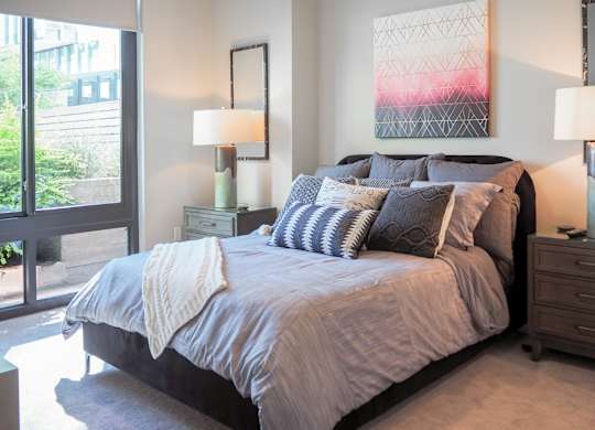 3 bedroom model bedroom with a bed and a big window at The Hamilton apartments in Dallas, TX