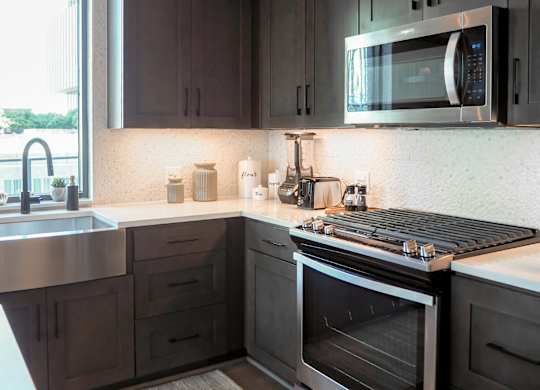 3 bedroom model kitchen with stainless steel appliances, quartz countertops, and a window at The Hamilton apartments in Dallas, TX