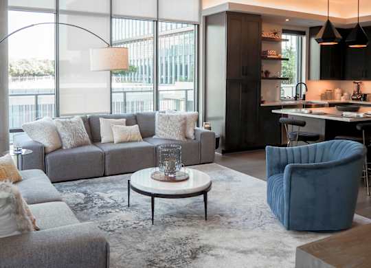 3-bedroom model living room with a gray couch and a blue chair at The Hamilton apartments in Dallas, TX