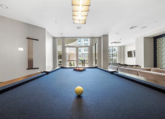 a game room with a blue pool table and a yellow ball on top of it at Harlow River Oaks in Houston, TX