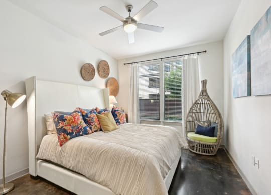 Model bedroom with a bed and a ceiling fan at Harlow River Oaks in Houston, TX