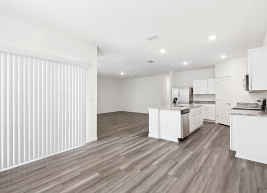 a kitchen and living room with wood floor and white walls