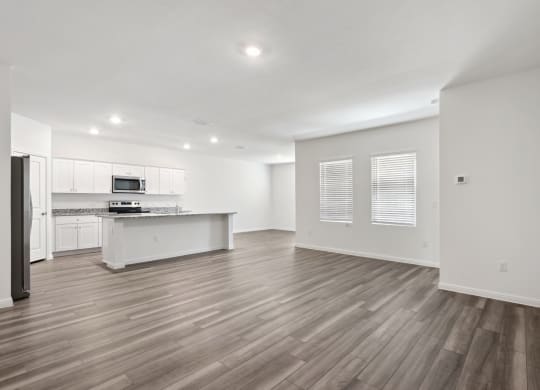 a living room and kitchen with windows and hardwod floors