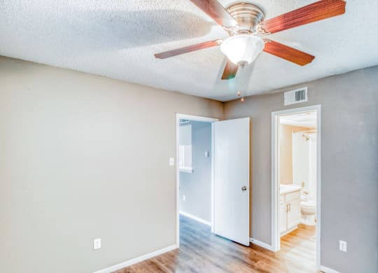 Unfurnished apartment bedroom with ceiling fan and private bathroom at Hillside Creek Apartments in Austin, TX