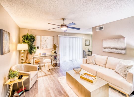 Model home living room with couch and ceiling fan at Hillside Creek Apartments in Austin, TX