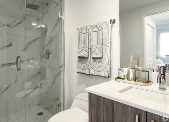 A bathroom with a marble walk-in shower and a white counter at Hollywood Heights on the Boulevard Luxury Apartments in Hollywood, FL