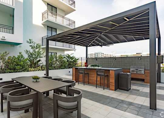 Outdoor grilling station with two BBQ grills and ample seating under a pergola at Hollywood Heights on the Boulevard Luxury Apartments in Hollywood, FL
