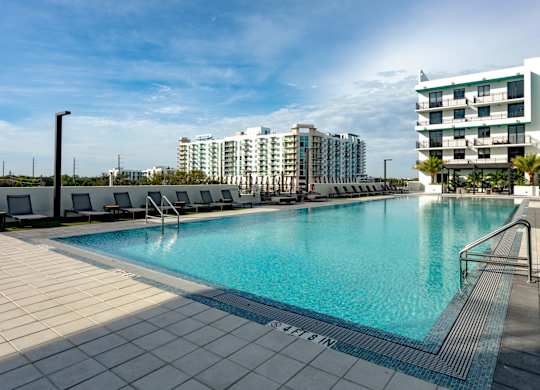 A large swimming pool with a tiled edge and a metal railing on our rooftop patio at Hollywood Heights on the Boulevard Luxury Apartments in Hollywood, FL