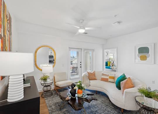 A living room with a white couch, a coffee table, and a mirror.