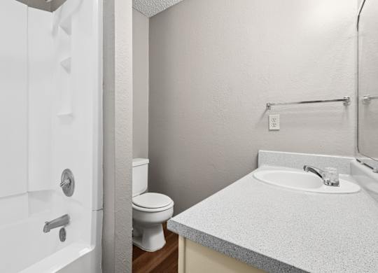 A bathroom with a toilet, sink, and bathtub at Heritage Square Apartments in Waco, TX
