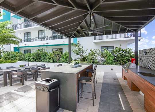 Outdoor grilling station with a table, chairs and a sink under a pavilion in our outdoor area at Hollywood Heights on the Boulevard.