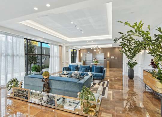 Lobby area with soft blue couches and elevators in the background at Hollywood Heights on the Boulevard Luxury Apartments in Hollywood, FL